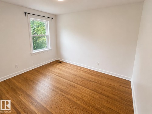 Bright room featuring wood-finish flooring, crisp white walls, and a recessed ceiling light - 12235 104 Street Nw, Edmonton, AB - Indoor Photo Showing Other Room