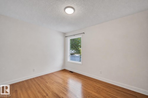 Bright room with wood-finish flooring and white baseboards - 12235 104 Street Nw, Edmonton, AB - Indoor Photo Showing Other Room