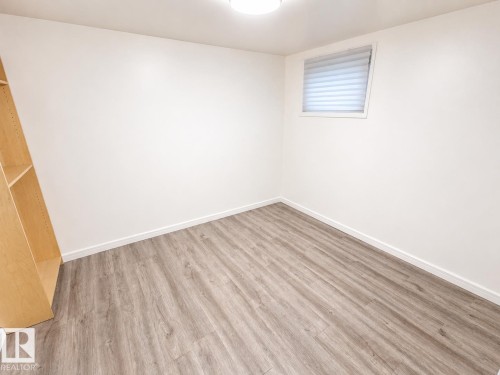 Room featuring wood-finish flooring, white baseboards, and a window with blinds - 12235 104 Street Nw, Edmonton, AB - Indoor Photo Showing Other Room