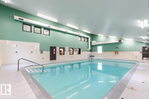 Indoor swimming pool featuring a light blue finish, integrated steps, and a metal handrail - #5 11265 31 Av Nw, Edmonton, AB - Indoor Photo Showing Other Room With In Ground Pool