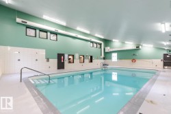 Indoor swimming pool featuring a light blue finish, integrated steps, and a metal handrail - 