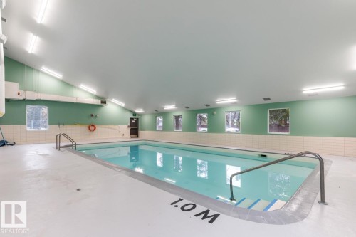 Indoor swimming pool with white deck surround, light green walls, and a vaulted ceiling - #5 11265 31 Av Nw, Edmonton, AB - Indoor Photo Showing Other Room With In Ground Pool