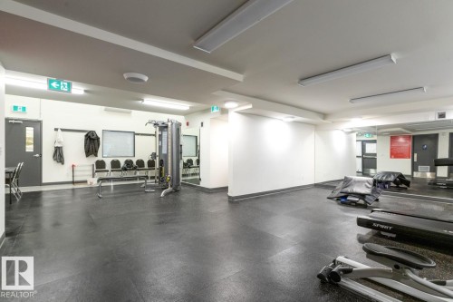 Spacious fitness studio featuring polished concrete flooring, abundant natural lighting from recessed ceiling fixtures, mirrored wall panels for form correction, and integrated equipment storage - #5 11265 31 Av Nw, Edmonton, AB - Indoor Photo Showing Gym Room