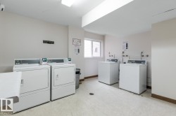 Community laundry room featuring multiple washing machines and dryers - 