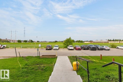 Concrete stairs with black metal railings opening onto a spacious green area - #5 11265 31 Av Nw, Edmonton, AB - Outdoor With View