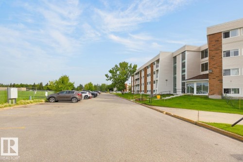 Multi-story building featuring light-toned siding, brick accents, multiple balconies, and a ground-floor sunroom - #5 11265 31 Av Nw, Edmonton, AB - Outdoor