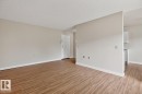 Spacious living area featuring wood-finish flooring, light neutral wall tones, and white baseboards - #5 11265 31 Av Nw, Edmonton, AB  - Indoor Photo Showing Other Room 