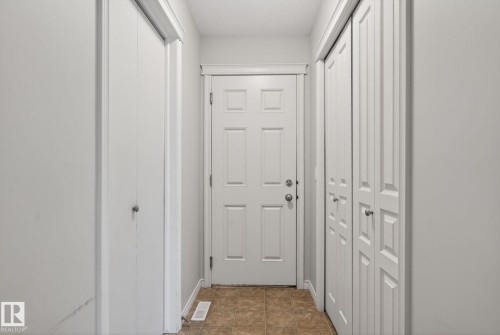 Bright foyer featuring multiple closet storage options, white six-panel entry door with sidelights, and neutral cork-finish flooring throughout - 96 Dalquist Bay, Leduc, AB - Indoor Photo Showing Other Room