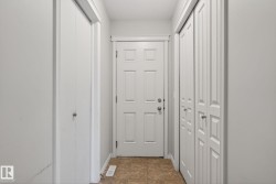 Bright foyer featuring multiple closet storage options, white six-panel entry door with sidelights, and neutral cork-finish flooring throughout - 