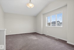 Spacious room featuring vaulted ceilings, a large multi-pane window, neutral-toned walls, gray carpeting, and a semi-flush mount ceiling light fixture - 
