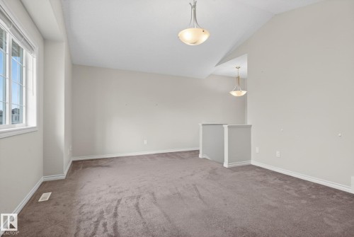Carpeted upper-level space featuring a vaulted ceiling and an interior window with divided lites - 96 Dalquist Bay, Leduc, AB - Indoor Photo Showing Other Room