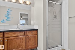 Bathroom featuring a single vanity with wood-finish cabinetry, a dark countertop, and an integrated sink - 