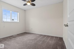 Bedroom featuring neutral-toned walls, grey carpeting, a multi-pane window, and a ceiling fan with integrated lighting - 