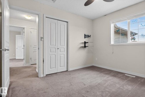 Carpeted interior room featuring a ceiling fan, a large window, bi-fold closet doors, and built-in wall shelving - 96 Dalquist Bay, Leduc, AB - Indoor Photo Showing Other Room