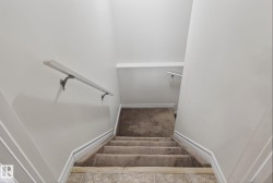 Carpeted staircase with white handrails and trim, leading to a tiled landing - 