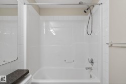 Bathtub and shower combination featuring a white surround, chrome showerhead with hose, and chrome fixtures - 