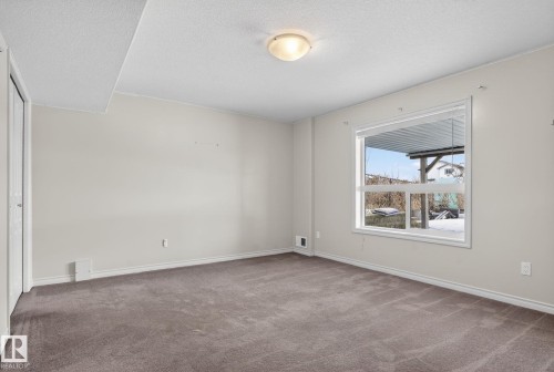 Spacious room featuring neutral carpeting, light-toned walls, and a large window with white trim - 96 Dalquist Bay, Leduc, AB - Indoor Photo Showing Other Room