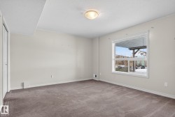 Spacious room featuring neutral carpeting, light-toned walls, and a large window with white trim - 