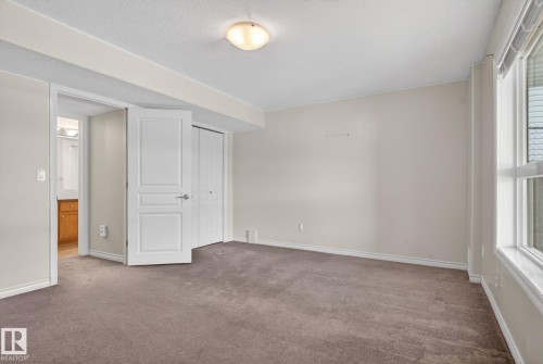 Neutral-toned room featuring broadloom carpet, white trim, and a window with horizontal blinds - 96 Dalquist Bay, Leduc, AB - Indoor Photo Showing Other Room