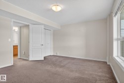 Neutral-toned room featuring broadloom carpet, white trim, and a window with horizontal blinds - 