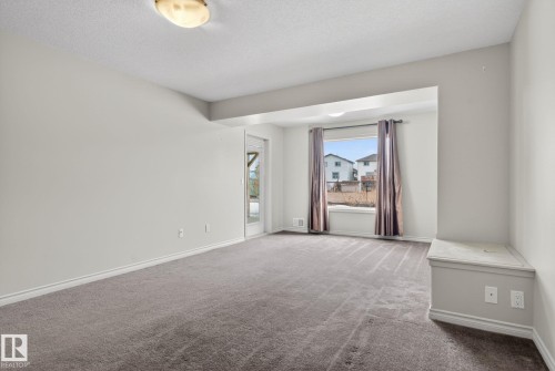 Carpeted room featuring a window with curtain rods, a built-in bench, and a flush-mount ceiling light fixture - 96 Dalquist Bay, Leduc, AB - Indoor Photo Showing Other Room