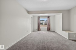 Spacious room featuring neutral carpeting, light-toned walls, a large window, and an integrated window seat with a built-in storage bench - 