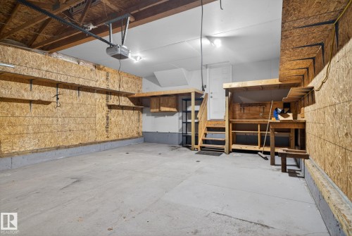 Spacious garage featuring a concrete floor, exposed ceiling joists, and built-in shelving - 96 Dalquist Bay, Leduc, AB - Indoor Photo Showing Garage
