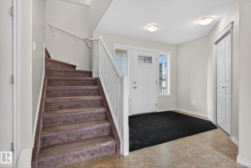 Welcoming foyer featuring a curved staircase with wood-finish treads and white spindle railing, recessed ceiling lighting, ceramic tile flooring, and direct entry to the main living spaces - 96 Dalquist Bay, Leduc, AB - Indoor Photo Showing Other Room