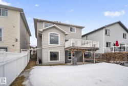 Rear exterior showcasing a raised wood deck with white railing, a ground-level patio, and a fenced perimeter - 
