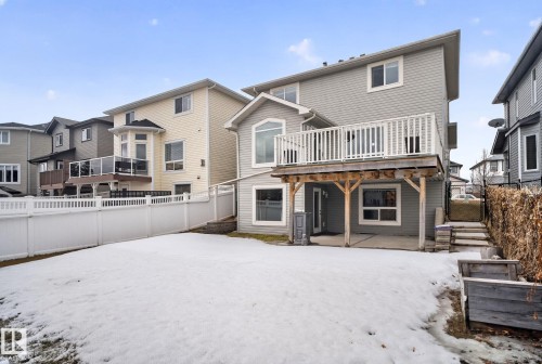Spacious backyard featuring a snow-covered lawn, wooden deck with white railings, and a detached two-story structure with finished basement level - 96 Dalquist Bay, Leduc, AB - Outdoor