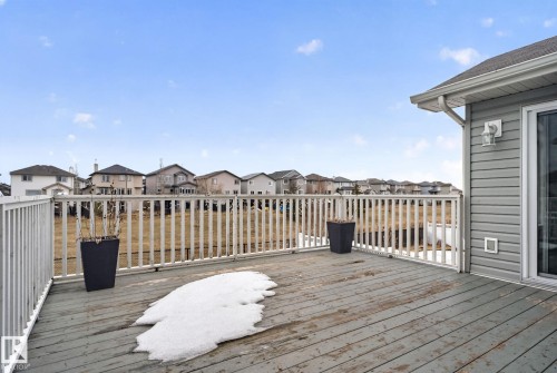 Expansive composite deck featuring white vinyl railing, wood-finish decking, and panoramic sightlines of the surrounding neighborhood - 96 Dalquist Bay, Leduc, AB - Outdoor With Deck Patio Veranda With Exterior