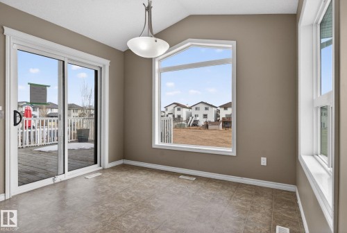 Spacious room featuring a unique trapezoidal window, sliding glass patio door, durable tile flooring, a contemporary semi-flush ceiling light, and neutral wall tones - 96 Dalquist Bay, Leduc, AB - Indoor Photo Showing Other Room