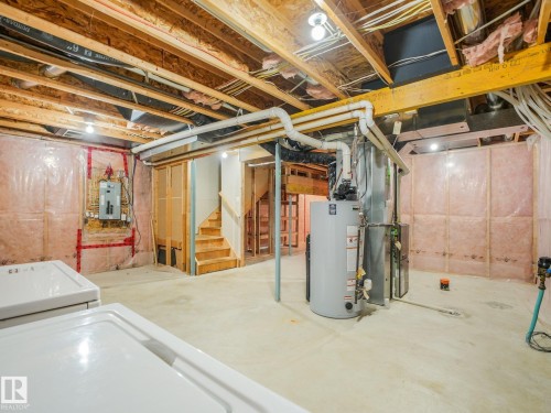 Unfinished basement featuring exposed wooden beam ceiling structure, concrete flooring, and mechanical systems including water heater and HVAC components - 11844 21 Avenue Sw, Edmonton, AB - Indoor Photo Showing Basement