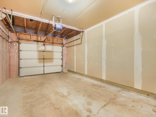 Concrete flooring garage with an overhead door, exposed wooden framing, and partial wall insulation - 11844 21 Avenue Sw, Edmonton, AB - Indoor Photo Showing Garage