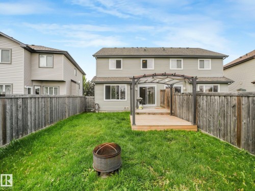 Spacious backyard oasis featuring a manicured lawn, mature wooden privacy fencing on both sides, and a composite deck with pergola structure - 11844 21 Avenue Sw, Edmonton, AB - Outdoor With Exterior