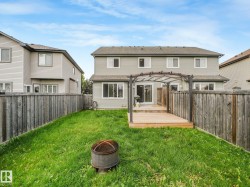 Spacious backyard oasis featuring a manicured lawn, mature wooden privacy fencing on both sides, and a composite deck with pergola structure - 