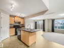 Open-concept kitchen and living area featuring natural wood cabinetry, stainless steel appliances, a dual-basin island with undermount sink, tile countertops, and polished concrete flooring - 11844 21 Avenue Sw, Edmonton, AB  - Indoor Photo Showing Kitchen With Double Sink 