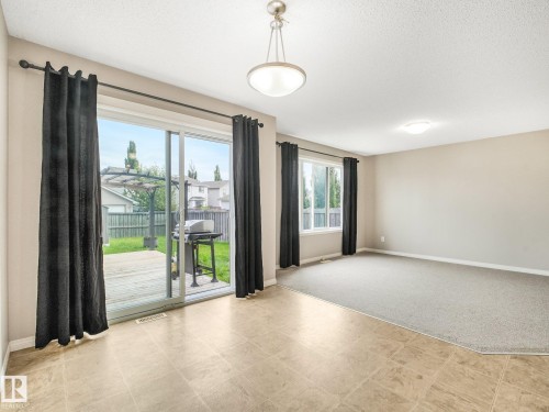 Spacious interior featuring a sliding glass patio door, direct access to an exterior wooden deck, and a fenced backyard - 11844 21 Avenue Sw, Edmonton, AB - Indoor Photo Showing Other Room