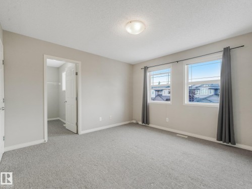 Spacious room featuring neutral carpeting, light-toned walls, and a ceiling-mounted light fixture - 11844 21 Avenue Sw, Edmonton, AB - Indoor Photo Showing Other Room