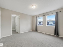 Spacious room featuring neutral carpeting, light-toned walls, and a ceiling-mounted light fixture - 
