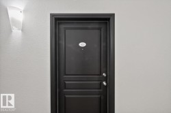 Dark paneled entry door with round door knobs and a door number plaque - 