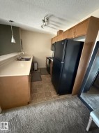 Kitchen featuring wood-finish cabinetry, black appliances, track lighting, and a peninsula with a pendant light - 