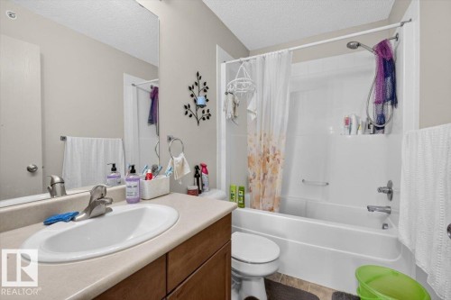 Bathroom featuring a vanity with an integrated sink, a large wall-mounted mirror, and a full bathtub with shower - #421 1180 Hyndman Rd Nw, Edmonton, AB - Indoor Photo Showing Bathroom