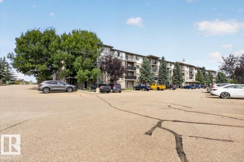 Multi-story residential building with light-colored siding and dark accents - #421 1180 Hyndman Rd Nw, Edmonton, AB - Outdoor