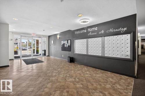 Building entrance featuring automatic glass doors, recessed ceiling lighting, and a mailroom wall with individual mailboxes - #421 1180 Hyndman Rd Nw, Edmonton, AB - Indoor Photo Showing Other Room