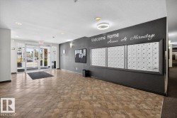 Building entrance featuring automatic glass doors, recessed ceiling lighting, and a mailroom wall with individual mailboxes - 