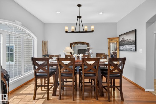 Spacious dining area featuring wood-finish flooring, a contemporary chandelier, recessed lighting, and a large arched window with grid detailing - 50336 Range Road 280, Rural Leduc County, AB - Indoor Photo Showing Dining Room