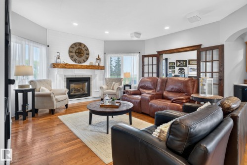 Living area featuring wood-finish flooring, a white shiplap accent wall, and a fireplace with a substantial wooden mantel - 50336 Range Road 280, Rural Leduc County, AB - Indoor Photo Showing Living Room With Fireplace