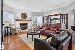 Living area featuring wood-finish flooring, a white shiplap accent wall, and a fireplace with a substantial wooden mantel - 