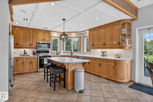 Kitchen featuring wood cabinetry, stainless steel appliances, a center island with seating, a coffered ceiling, and tiled flooring - 50336 Range Road 280, Rural Leduc County, AB - Indoor Photo Showing Kitchen